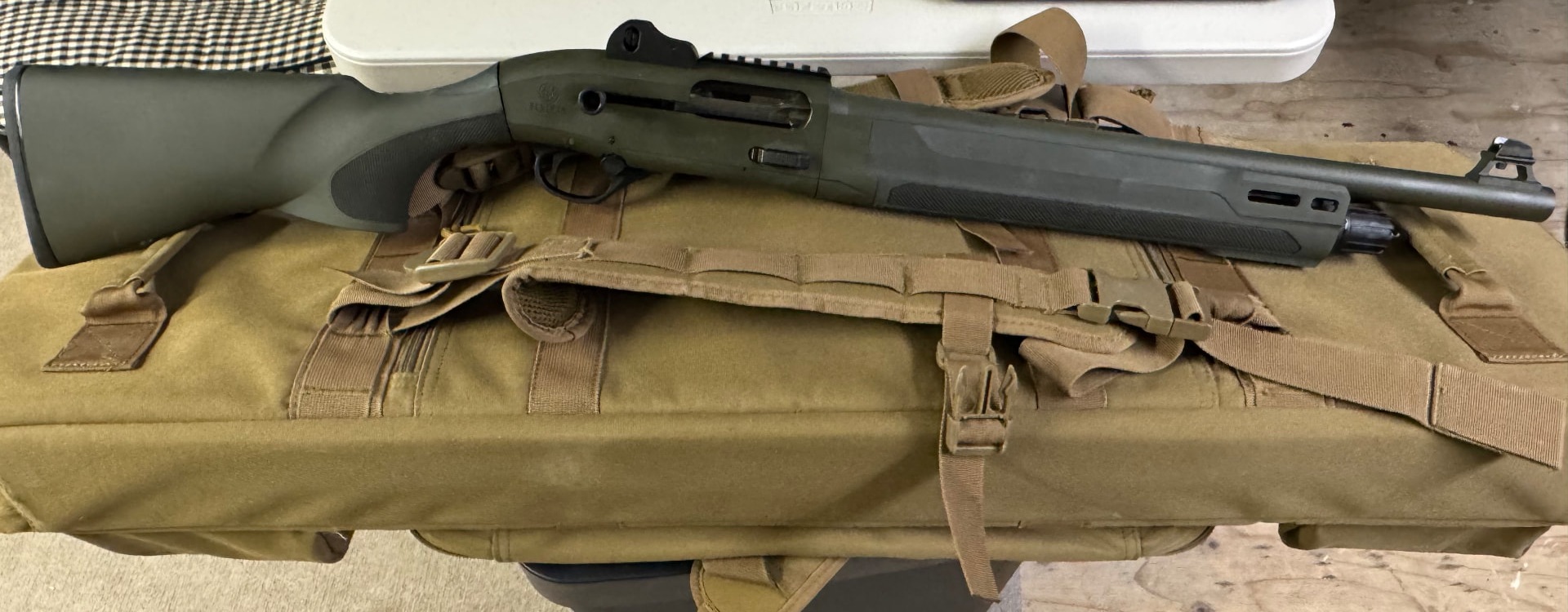 Beretta 1301 shotgun resting on an olive range bag